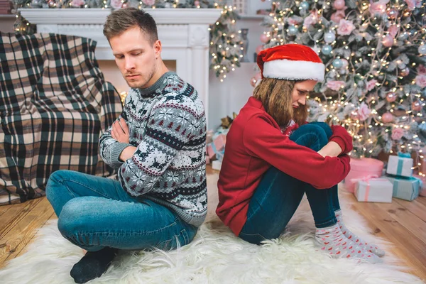 Wütende und aufgebrachte junge Männer und Frauen lehnen sich zurück. Sie schauen sich nicht an. Mann drückt die Hände. Frau umarmt ihre Beine. Sie kleideten sich festlich. — Stockfoto