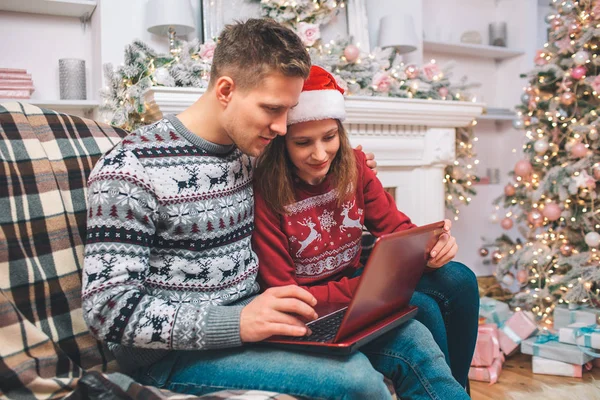 Hombre y mujer joven concentrado e interesado trabaja usando el ordenador portátil. Lo miran. El tipo presiona botones. Llevan ropa festiva. . — Foto de Stock