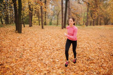 Dışarıda koşu mutlu bir genç kadın. O kulaklık üzerinden müzik dinlemek. Genç kadın gülümsüyor. O tek başına çalışır.