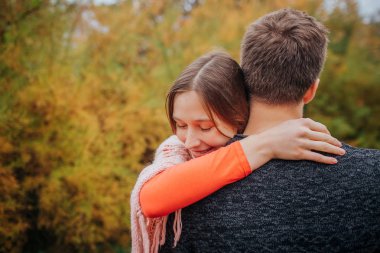 Genç kadın stand ve ebrace adam. Alnına başını tutar. Parkta olduklarını.