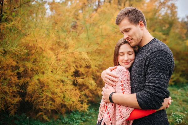 Preciosa foto de pareja abrazándose. Mantienen los ojos cerrados y disfrutan del momento. La gente está en el parque de otoño . — Foto de Stock