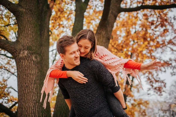 Imagem de casal adorável passar o tempo no parque. Ela abraçou-o. Ele segura-a de costas. Outono no exterior . — Fotografia de Stock