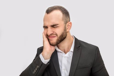 Genç sakallı adam diş ağrısı muzdarip. Elini yanağına tutar ve gözlerini kapalı tut. Beyaz arka plan üzerinde izole.