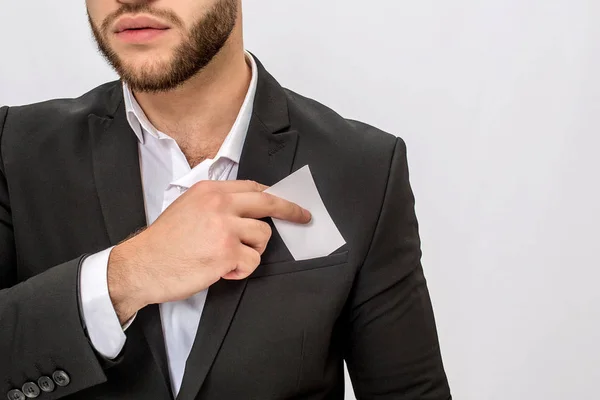 Vue coupée du jeune homme barbu tient morceau de tissu blanc. Il l'a mis dans sa poche. Le jeune homme porte un costume. Isolé sur fond blanc . — Photo