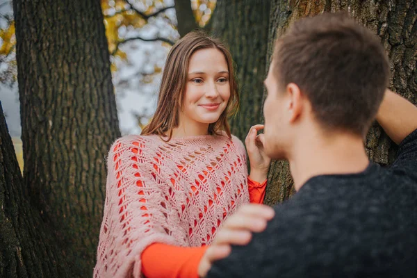 Młoda kobieta spojrzenie na człowieka i uśmiech. Ona jest w miłości. Kobieta dotyka go. Opiera się on na drewno. — Zdjęcie stockowe