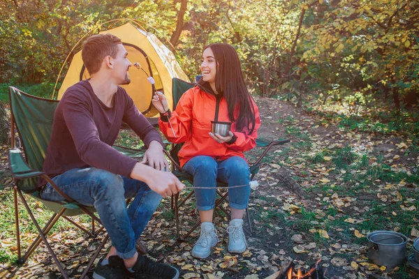 Zabawny młoda kobieta stara się karmić swojego chłopaka z murshmellow. Patrzy na niego i śmiejąc się. Siedzi facet na nią i uśmiecha się. Są szczęśliwi. — Zdjęcie stockowe