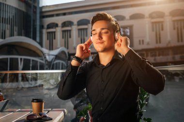 Mutlu genç adam talbe dışında oturup ve kulaklık ile müzik dinleyebilirsiniz. O Nemrud'a bu. Adam kulaklıktan tutuşsun. Güneşli.