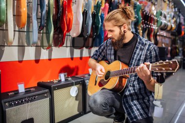Oturma ve akustik gitar çalmaya genç hippi. Aşağıya bakar. Yoğun biri. Birçok elektronik gitar ve ses sütunları geride kaldı.