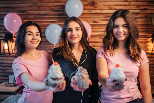 Drei junge Frauen stehen und schauen in die Kamera. Sie trauten sich. Die Leute halten drei Kuchen in den Händen. Sie zeigen es vor der Kamera. Es sieht lecker aus. junge Frauen haben Party im Zimmer. — Stockfoto