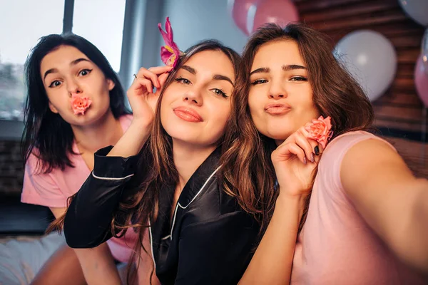 Jovens divertidas e simpáticas posando na câmera. Garota à direita, segure. Os modelos estão no quarto. Muitos balões coloridos estão por trás deles . — Fotografia de Stock