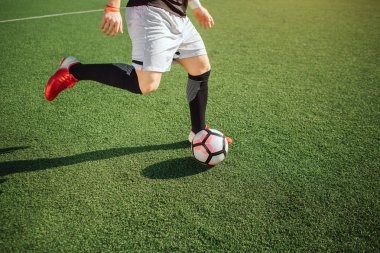 Futbol oynayan adam resmi. O topu tekmeyi basacak. Adam sahada tek başına oynuyor. Dışarıda güneşli. Kesme görünümü.