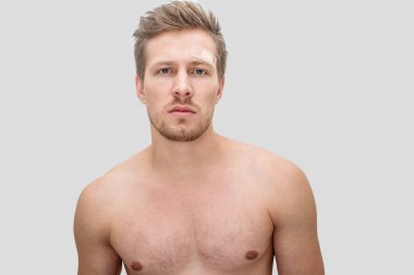 Ciddi ve yoğun genç adam kameraya bakıyor. Gömleksiz o. Beyaz arka plan üzerinde izole.