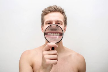 Mutlu genç adam onun dişlerinin arasından Büyüteç gösterilen. Düz görünüyor. Beyaz arka plan üzerinde izole.