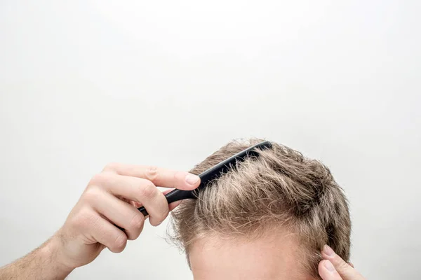 Vista corte do jovem loiro escovar o cabelo. Isolado sobre fundo branco . — Fotografia de Stock