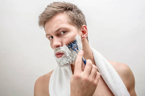 Retrato de um jovem barbeado. Tem espuma branca na barba. O tipo é sério e concentrado. Isolado sobre fundo branco . — Fotografia de Stock