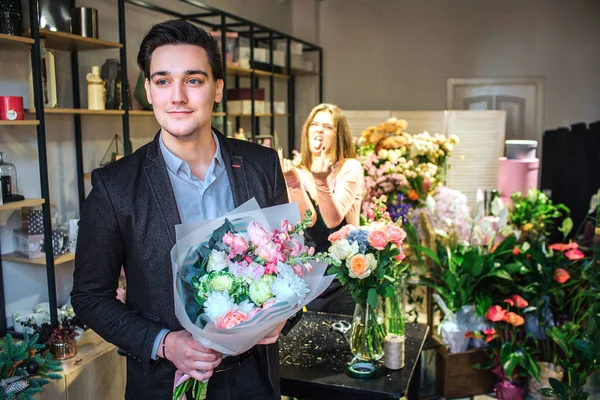 Joven hombre de negocios guapo de pie en la florería. Tiene el ramo en las manos. Está solo en la habitación. . — Foto de Stock