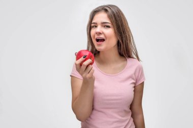 Çekici genç kadın elma elinde tut. Ağzını açtı. Düz görünüyor. Gri arka plan üzerinde izole.