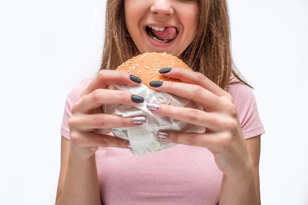 Gesneden beeld van jonge man Hamburger bedrijf in handen. Ze likken de lippen met tong. Geïsoleerd op witte achtergrond. — Stockfoto