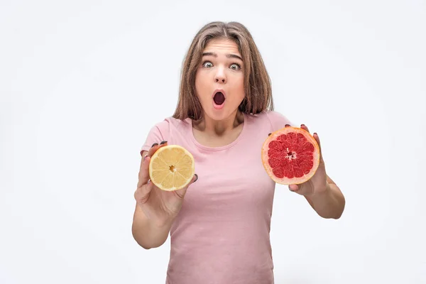 Die aufgeregte junge Frau hält die Hälfte von Leman und Grapefruit in der Hand. Sie zeigt es vor der Kamera. Modellwunder. isoliert auf weißem Hintergrund. — Stockfoto
