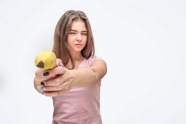 严肃的年轻女子拿着香蕉就像枪一样。隔离在灰色背景上. — 图库照片