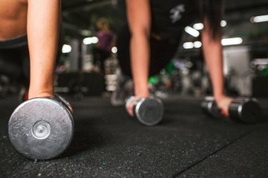 İki çift görünümünü dumbbells üzerinde duran genç kadın ellerini kesti. Spor salonunda aynı katta çalıştıkları.