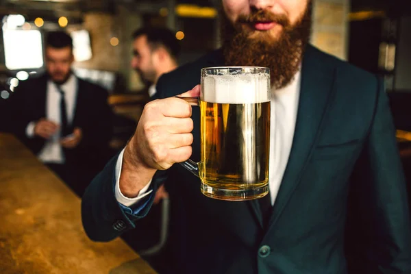 Takım elbise tutun bira bardağı içinde sakallı adam görünümünü kesti. Diğer iki ofis çalışanları arkasında oturmak. — Stok fotoğraf
