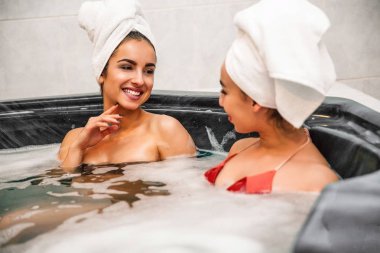 Avrupa kadın olumlu ve güzel gülümseme onun arkadaşı. Jakuzide köpük su dolu oturuyorlar. Onlar konuşmak ve birlikte vakit geçirmek.