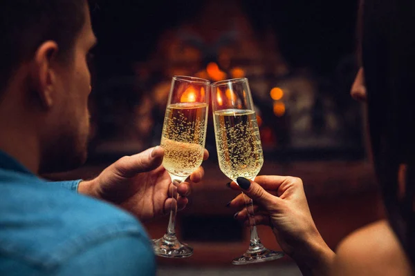 Joven hombre y mujer gafas táctiles con champaigne. Se miran unos a otros. Pareja sentarse en la chimenea . — Foto de Stock