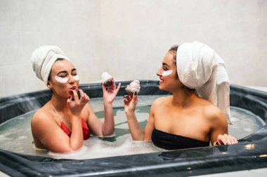 Güzel genç kadınlar jakuzide oturup krep yiyeceğim. Elinde onlarda. Asya modeli parmaklarını yalıyor. Kadınlar rahatlama ve eğlence var.