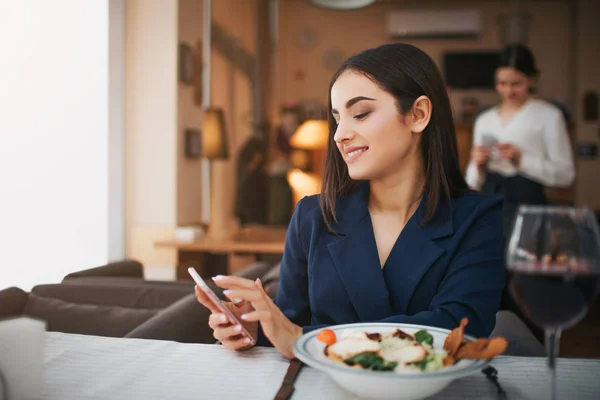 Fröhliche Junge Frau Hält Telefon Den Händen Und Lächelt Sie — Stockfoto