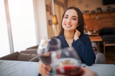 Neşeli yougn kadın kırmızı şarap basılı tutarak başka bir dokun. Gülümse ve yalındır görün.