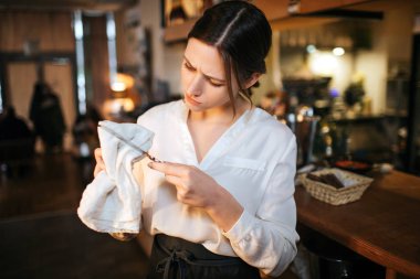 Meşgul genç garson standında bar ve bıçak silin. Bunda ciddi görünüyor. Yougn restoranda iş kadın.
