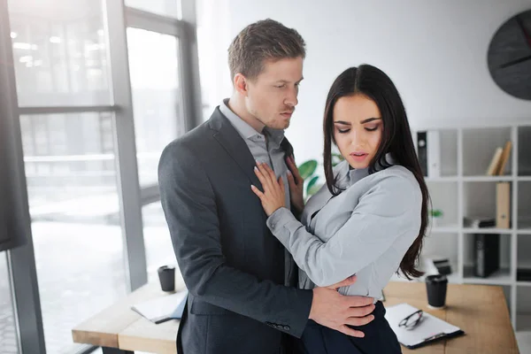 Begrip intimidatie. Rustige en stille jonge brunette kijk naar beneden. Ze houden de handen op mann borst. Ze wil niet intieme relaties met hem. Guy omhelzing brunette. — Stockfoto