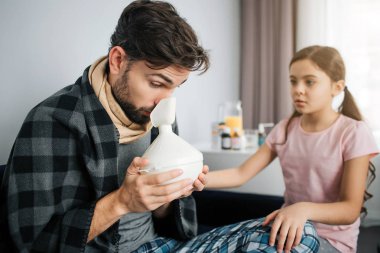 İnhalasyon yordamlar yapan hasta genç erkek. Yangın önleyici donatım tutun fo bu. Onun dışında bir odada oturup endişe küçük kız.