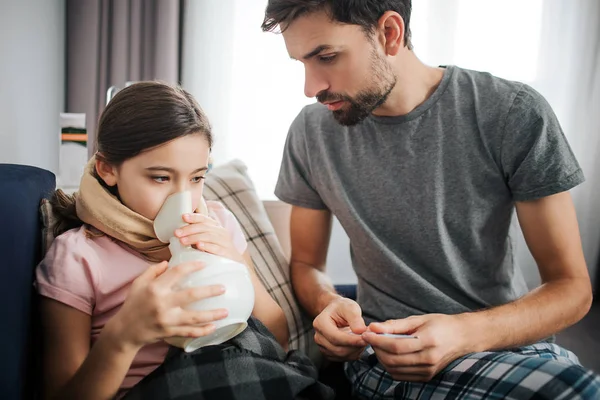 Genç adam resmi yanı sıra hasta kızı yatağa otur. İnhalasyon tedavisi var. Adam kontrol o.
