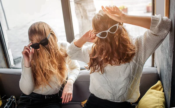 Imagem engraçada de mulheres jovens segurando solas na cabeça com cabelo. Eles posam e se divertem . — Fotografia de Stock