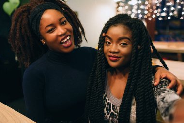 İki genç Afrika modelleri düz bakmak ve poz. Gülümse ve birlikte kafede oturup.