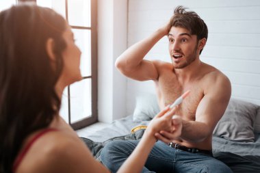 Hayret genç adam kadına bak ve gebelik testi ile onun elini tut. Sevindi. Onlar yatağa otur. Mutlu kadın şuna bak.