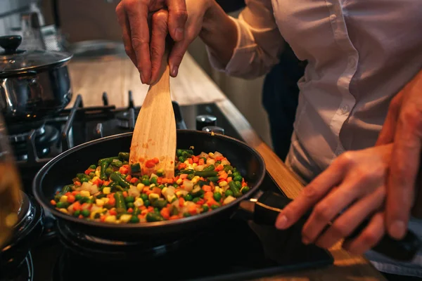 Skär syn på mannen som håller händerna på kvinnans. De laga middag tillsammans. Par steka mat på pan. — Stockfoto