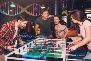 Hevesli genç adam ve kadın odada tablo futbol oynamayı çok heyecanlı. Onların arkadaşları yanında durmak ve tezahürat.