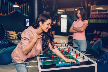 Genç esmer yalın Oda oynarken tablo futbol için mutlu. Onun arkadaşı üzülüyor. O el ele tutuşsun geçti.