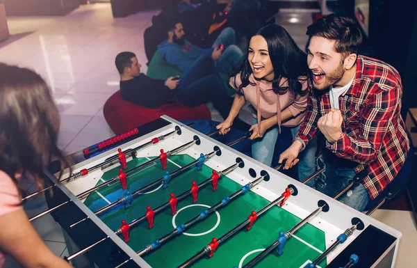 Happy young man and woman playing together in room. Intense game. Winning and loosing. Opponents at table soccer. — Stock Photo, Image