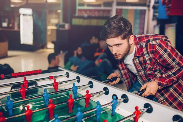 Young man playing alone at table soccer in room. Intense game. Guy looks concentrated. — Stock Photo, Image