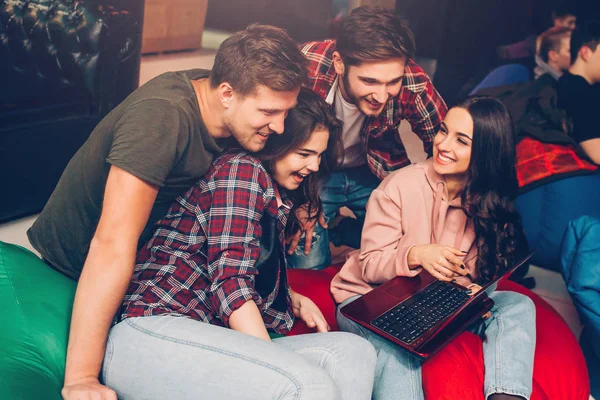 Des gens joyeux et heureux s'assoient ensemble dans la salle de jeux. Ils regardent l'ordinateur portable ensemble. Le sourire des gens . — Photo