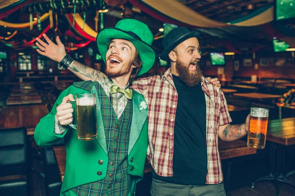 Boldog fiatalember gazdaság bögre sört, és énekel együtt pub. Hogy megünnepeljük a saitn Patrik napi. A srác a bal kopás zöld színű. — Stock Fotó
