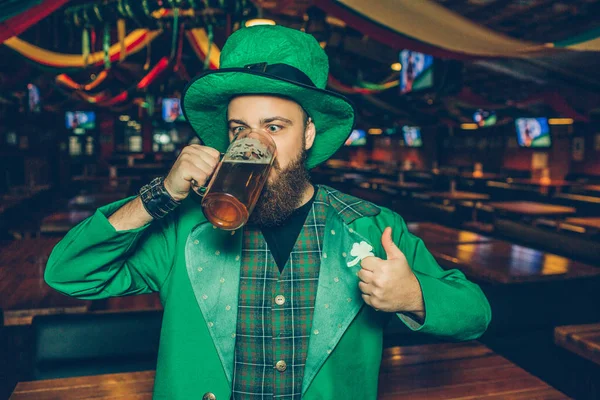 Kép fiatal férfi a kocsmába, ivott sört, a bögre zöld színű. Nagy hüvelykujj tartsuk lenyomva. — Stock Fotó