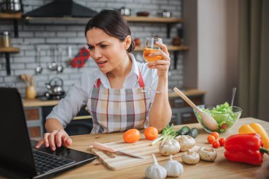 Rahatsız kadın mutfaktaki masada oturuyor. Elinde şarap kadehi ve klavyede daktilo vardı. Dizüstü bilgisayar ekranında manken görünümü. Duygusal biri..