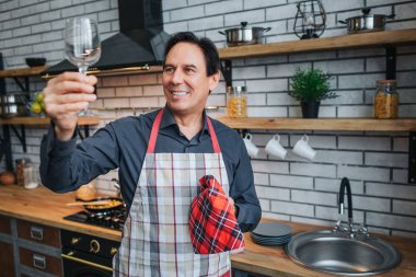 Önlük güzel yetişkin adam tek başına ve cam mutfak bakın. O Parlatıcı cleaness ile. Adam tutun mutfak havlusu ve gülümseme.