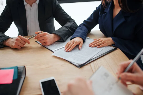 Gesneden beeld van mensen die samenwerken aan één tafel in de kamer. Één persoon schrijven in notitieblok. Anoter punt in boek. Guy Houd pen. — Stockfoto