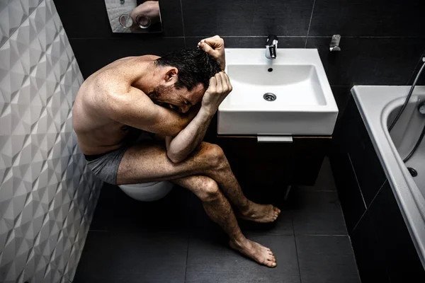 Hombre desnudo sentado en el baño de la vieja ciudad. La persona siente terrible dolor emocional e impotencia. El adicto se siente mal. . — Foto de Stock